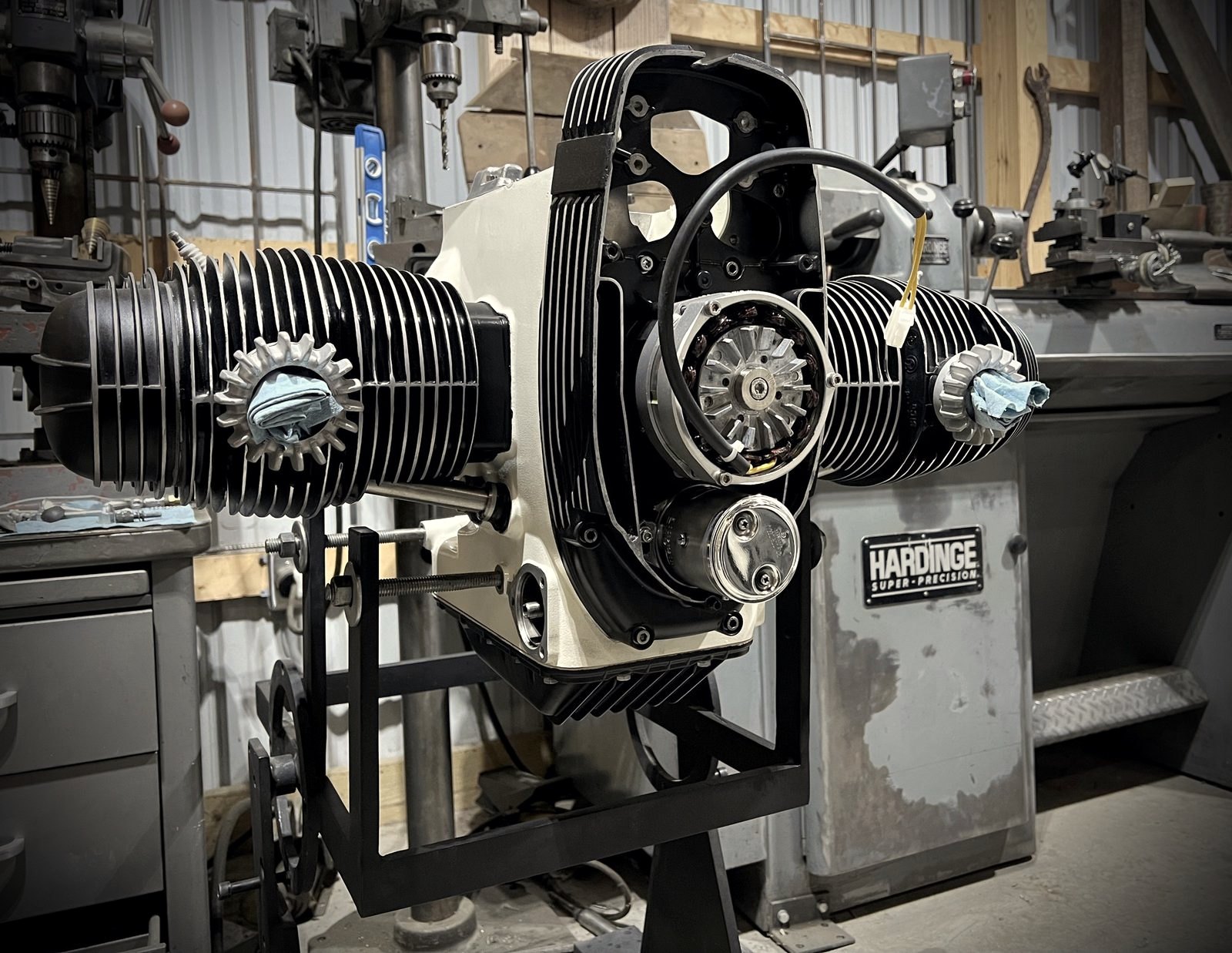 A rebuilt BMW boxer engine on a stand in front of a Hardinge lathe