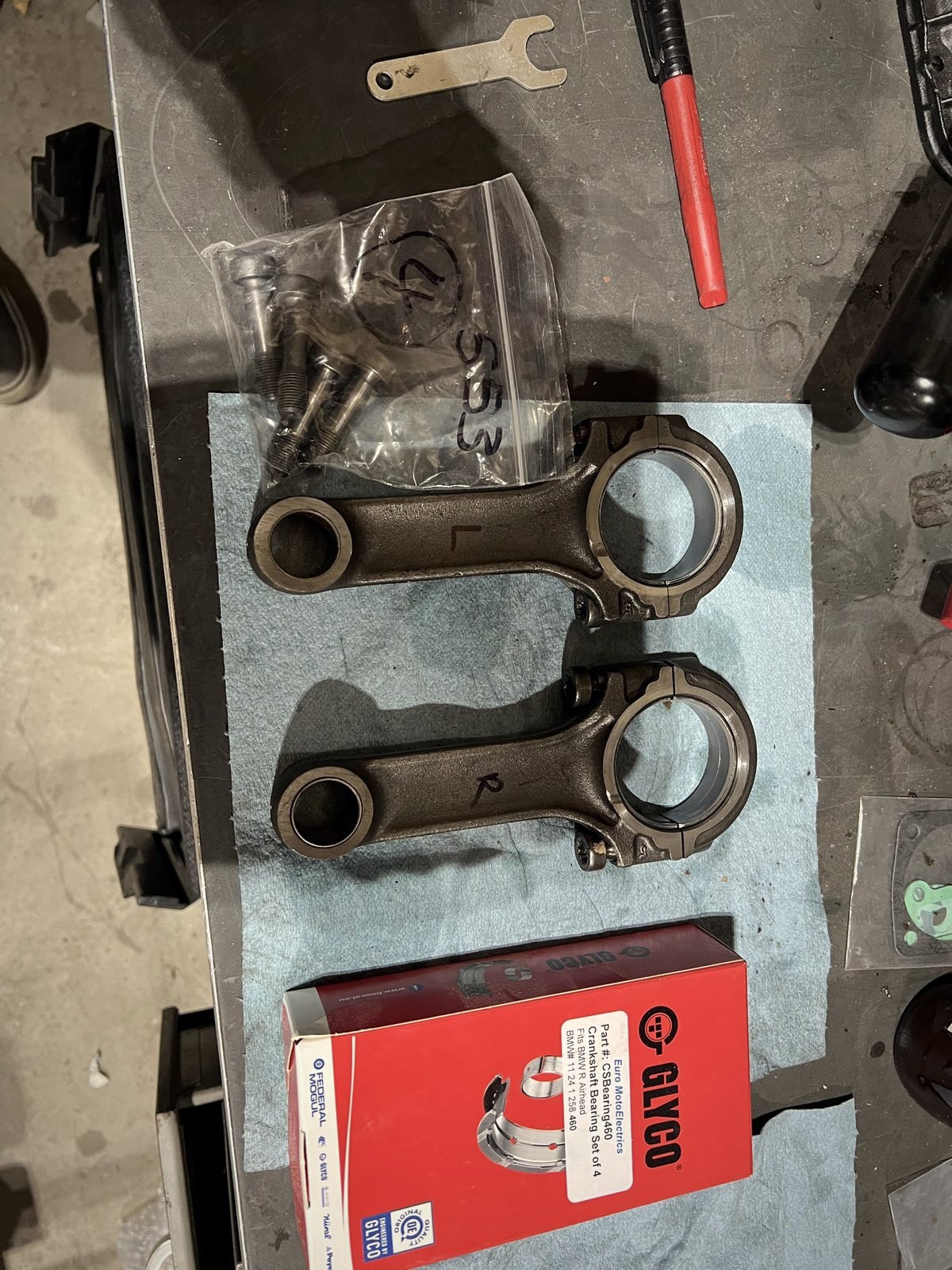 Two connecting rods on a blue shop towel beside a box of Glyco bearing shells